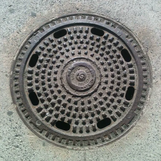 A round cast-iron manhole cover set in concrete