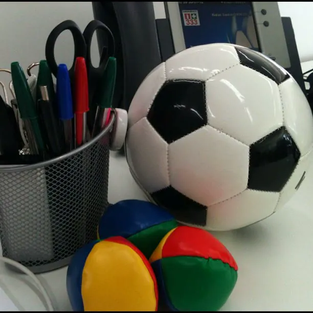 A desk with a football, juggling balls and a pot of pens and scissors