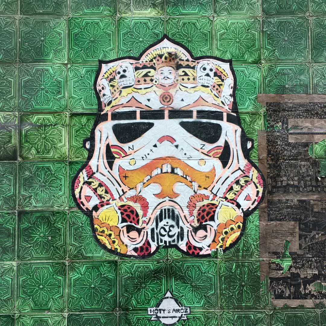 Street art in Lisbon: a decorated stormtrooper helmet on a wall of green tiles