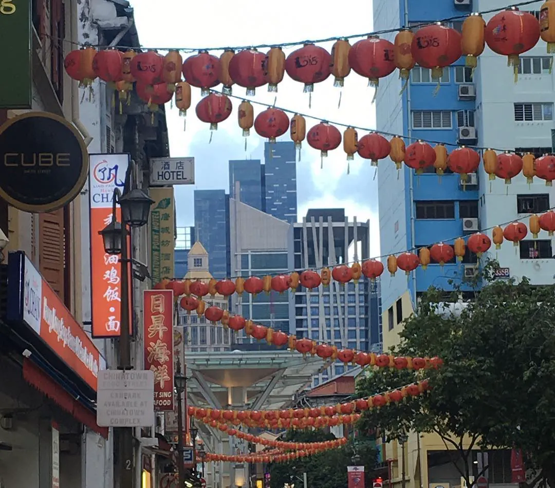 Red lanterns strung across a street in Chinatown, Singapore, with towers behind